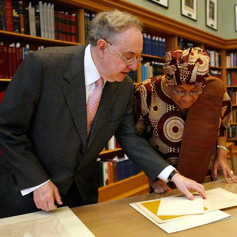 Patrick O'Meara and Ellen John Sirleaf examine a paper on a table.
